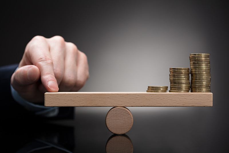 手指在跷跷板上平衡堆叠的硬币