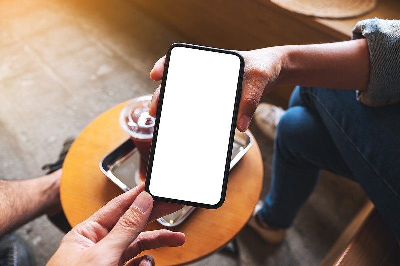 一名女子向一名男子展示一台桌面空白的手机