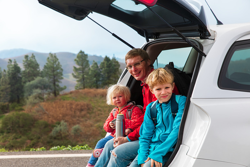 快乐的父亲带着孩子在大自然中开车旅行