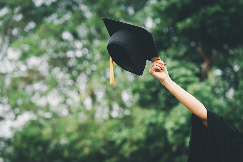 毕业帽扔在绿色背景成功毕业的大学，概念教育祝贺大学毕业生。