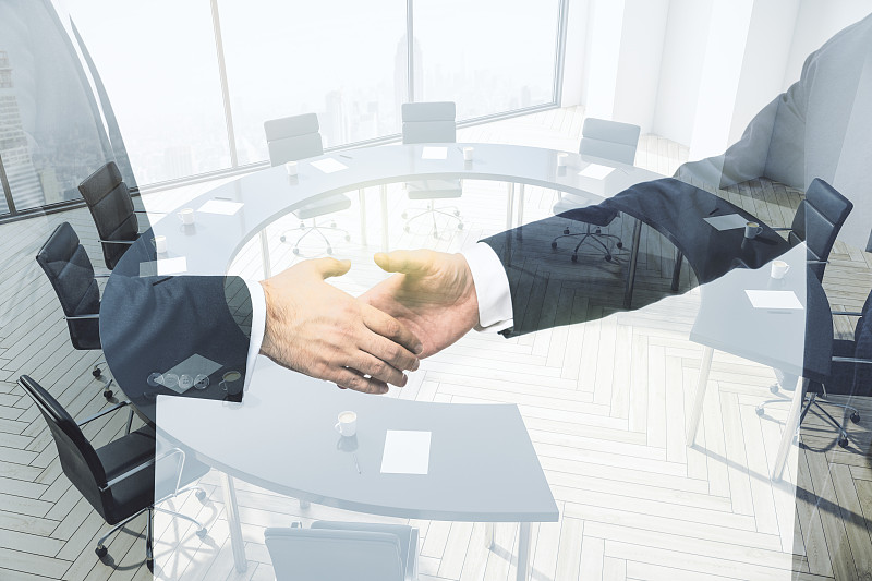 两位商务人士在会议室室内背景、合作与合作理念上的双重曝光握手