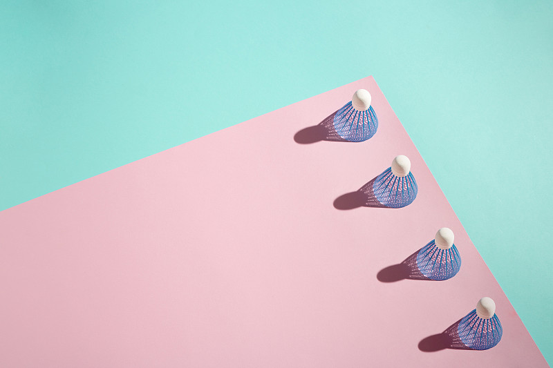 羽毛球(小鸟)堆叠在粉红色和蓝色的背景。副本的空间。