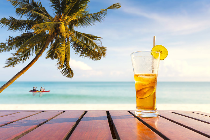 热带海滩上的椰子树和果汁饮料。户外活动。