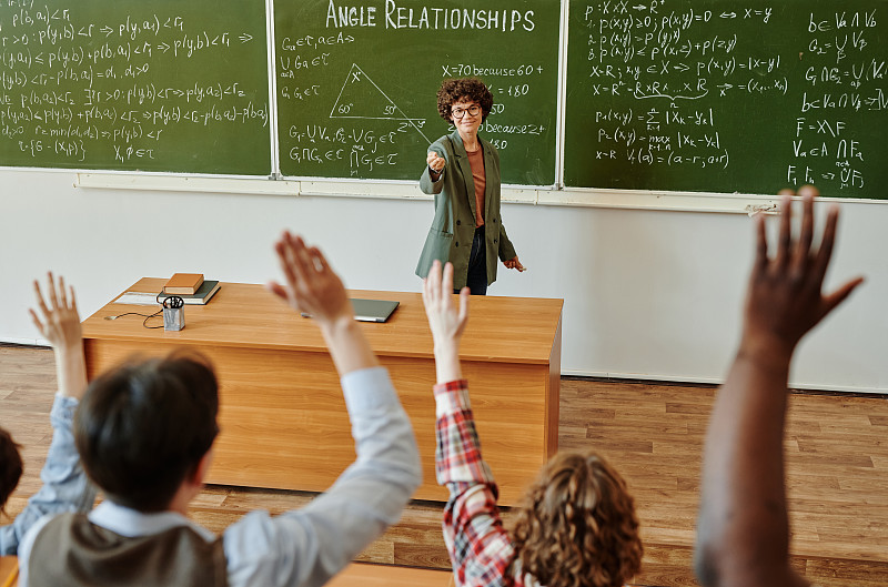 成功的老师指着一名跨种族学生举起的手