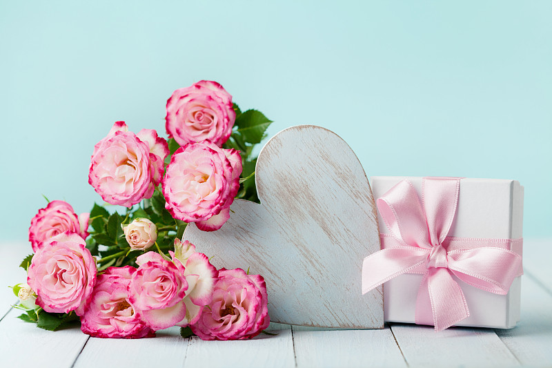 礼品或礼品盒，粉红色的花和木制的心在古董桌上。生日、妇女或母亲节贺卡。