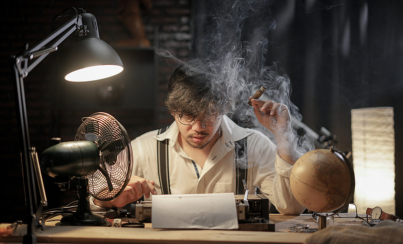 压力山大的男人抽雪茄寻找打字工作的灵感。50年代的场景设置。