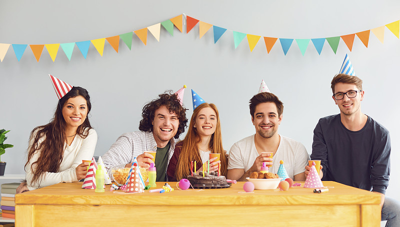 快乐的生日聚会。一群朋友拿着一块蛋糕祝女孩生日快乐