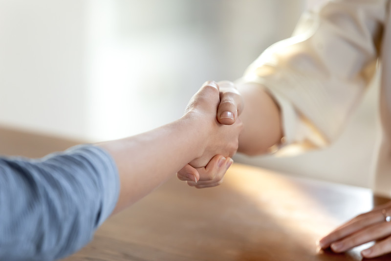 靠近两个女人握手，达成商业协议。