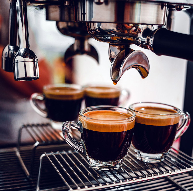 在咖啡店准备两杯浓缩咖啡时，专业的浓缩咖啡机。浓缩咖啡从咖啡机倒出来的特写镜头