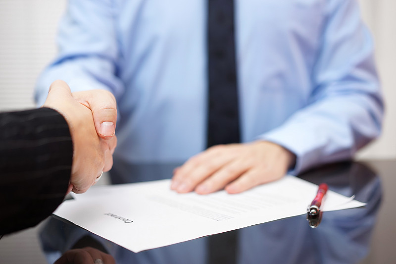 商人和女商人正在握手签署合同，合作的概念