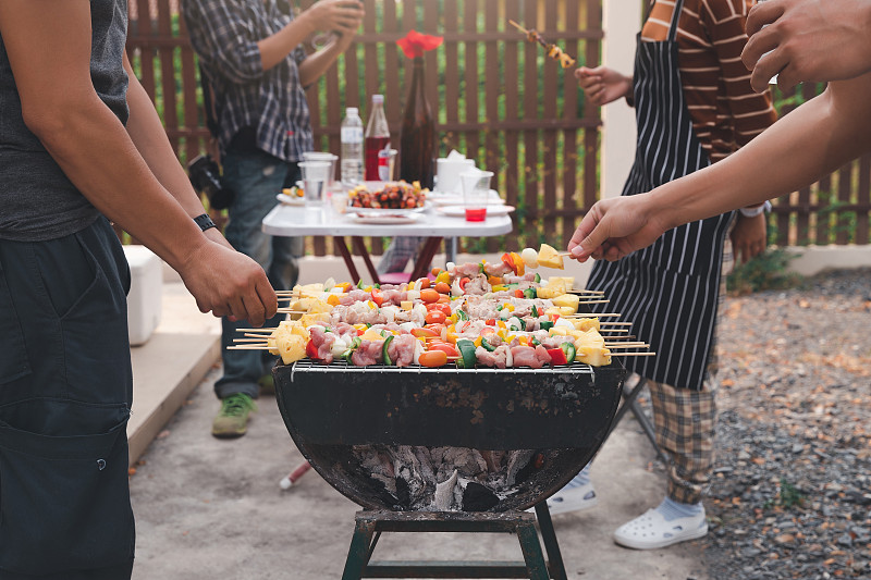 男人们在宴会上烤猪肉和烧烤。食物、人和家庭时间观念。