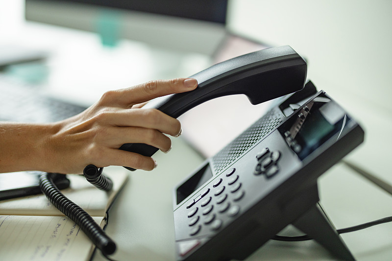 客户代表在使用固定电话的同时用电脑工作