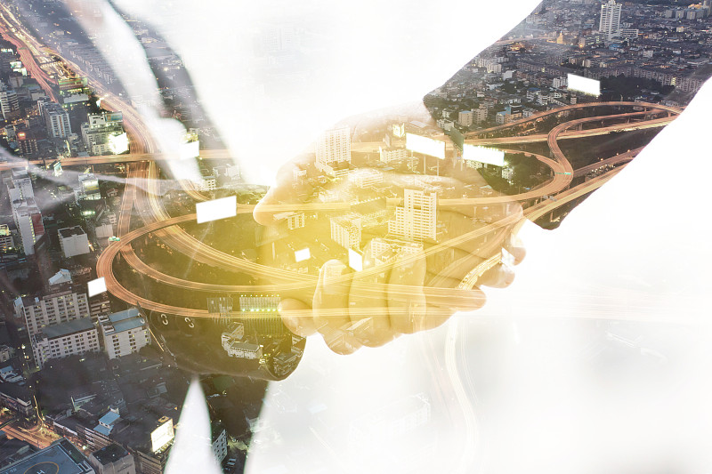 双曝光握手与夜色城市模糊的背景。