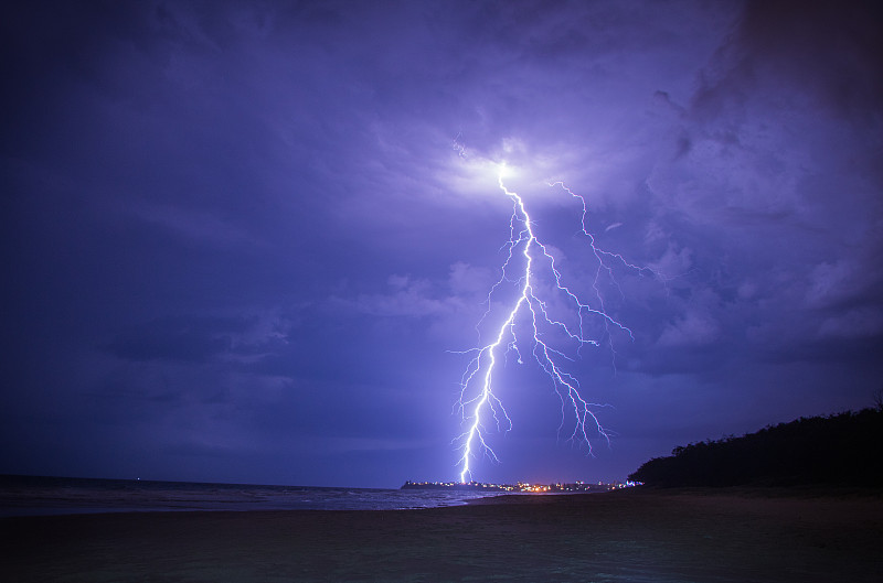 闪电在一个暴风雨的夏夜，与城市的灯光在远处。