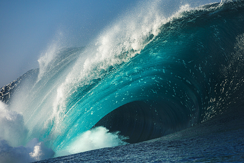 在一个阳光明媚的日子里，强大的蓝色和蓝绿色的波浪在开阔的海洋中劈开