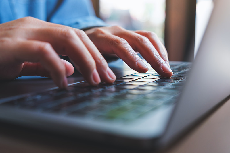 一个女人在笔记本电脑键盘上工作和打字的特写图像