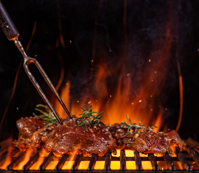 烤架上的牛排，背景是火焰