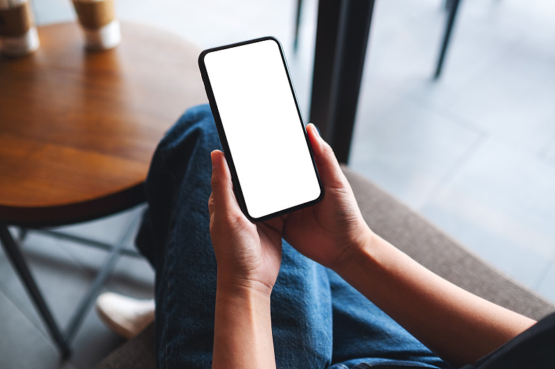 一个女人拿着手机和空白的白色桌面屏幕