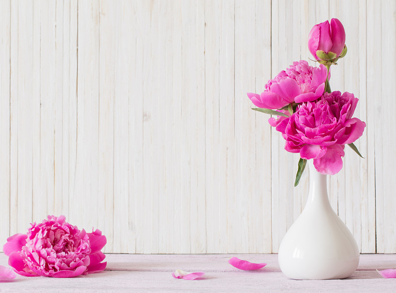 白木背景上的花瓶里插着牡丹