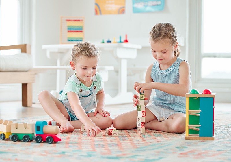 两个小女孩在家里玩玩具的照片