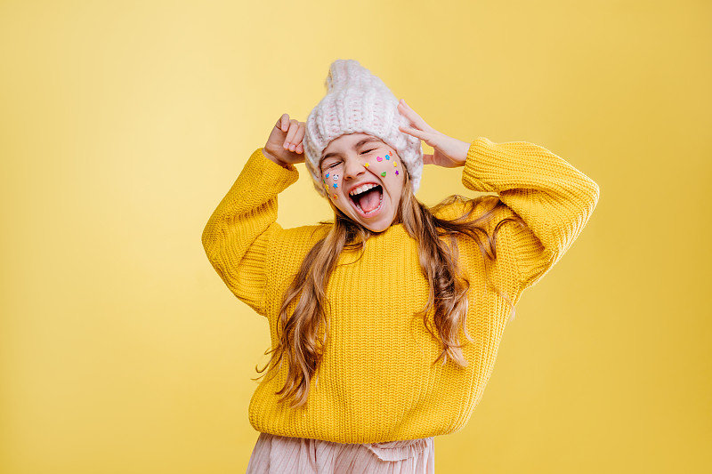 可爱的十几岁女孩与贴纸在她的脸在黄色的背景摆姿势