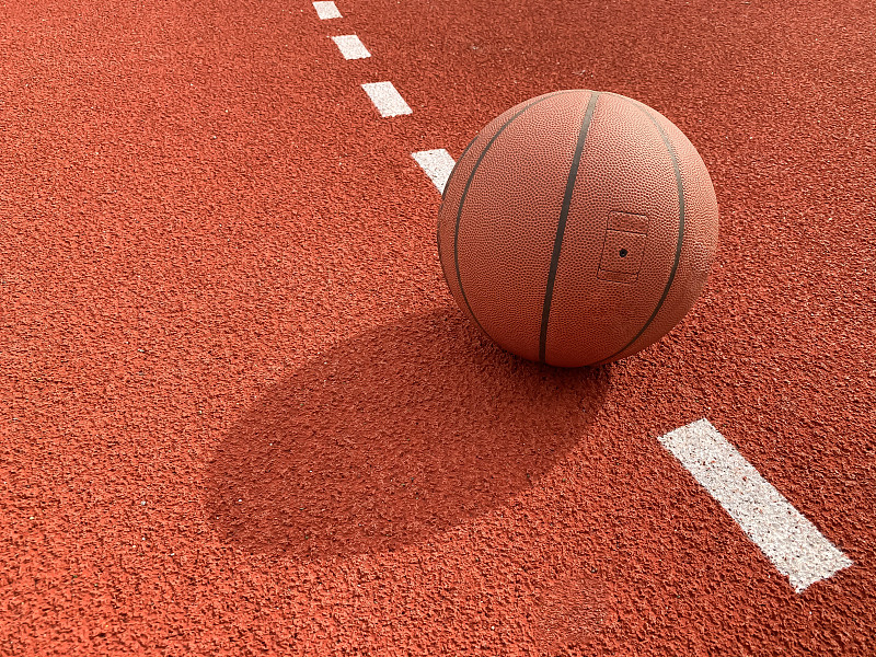 篮球场上的一个棕色皮球。背景。
