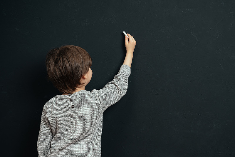 小男孩用粉笔在黑板上写了一些东西