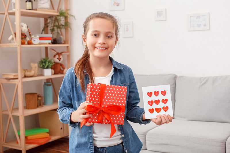 微笑和十多岁的女孩手里拿着礼物盒和明信片