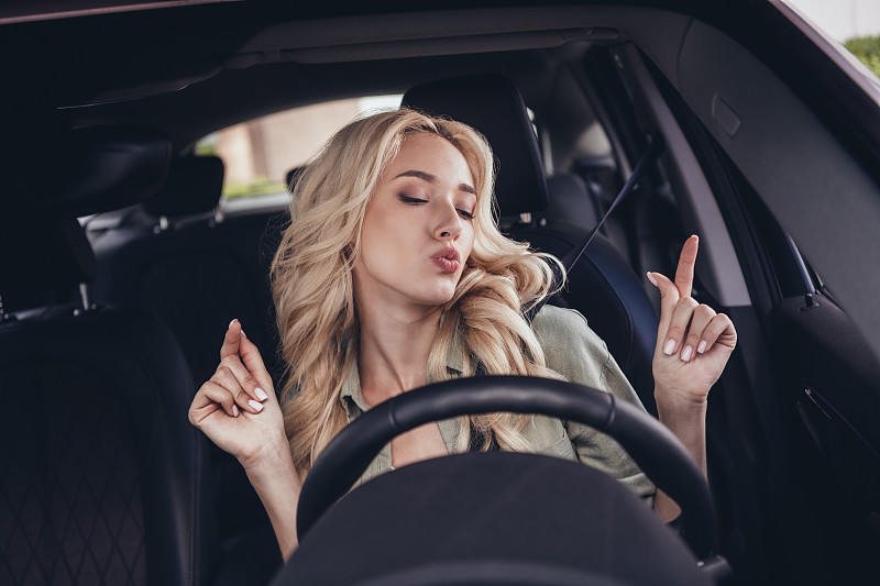 相当积极兴奋的女孩肖像驾驶汽车坐在前排手指享受播放列表