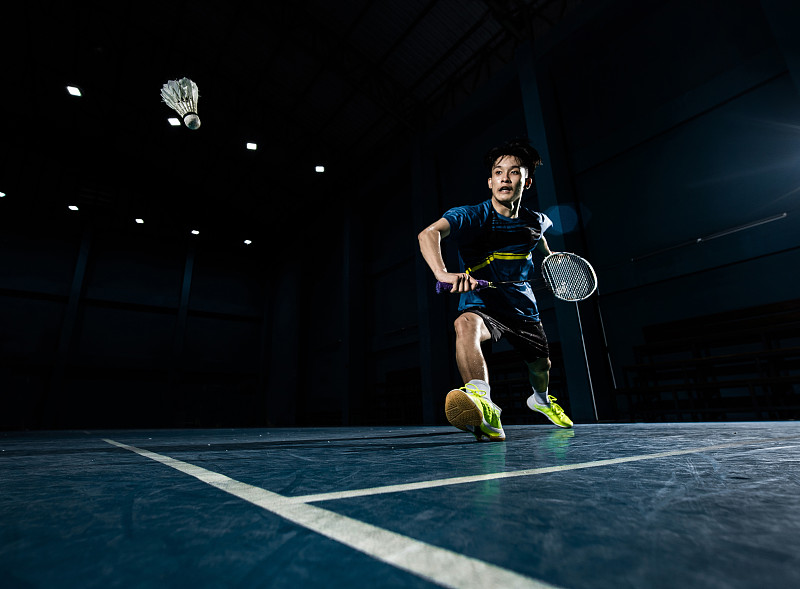 亚洲羽毛球运动员正在球场上击球