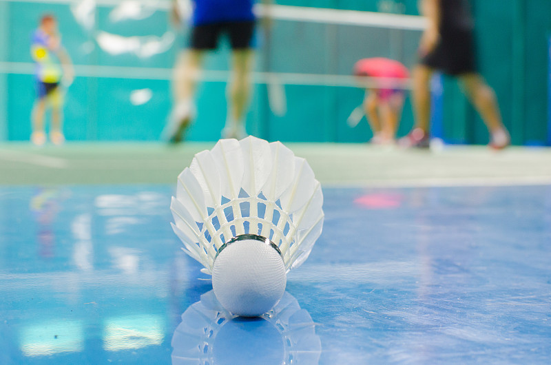 与羽毛球运动员一起在球场的地板上踢毽子