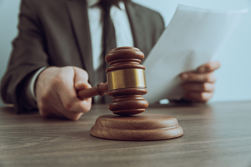 法官拿着文件，用木槌敲击