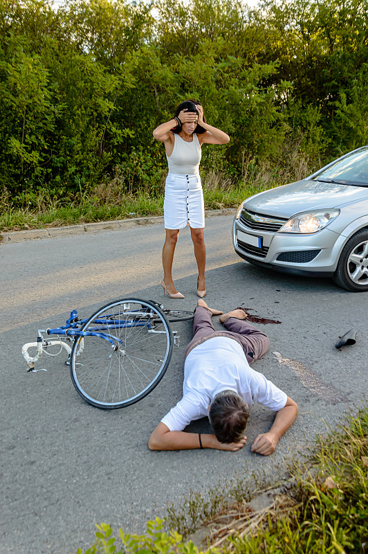 一个开车的女人在路上撞到了一个骑自行车的人，她感到很震惊。