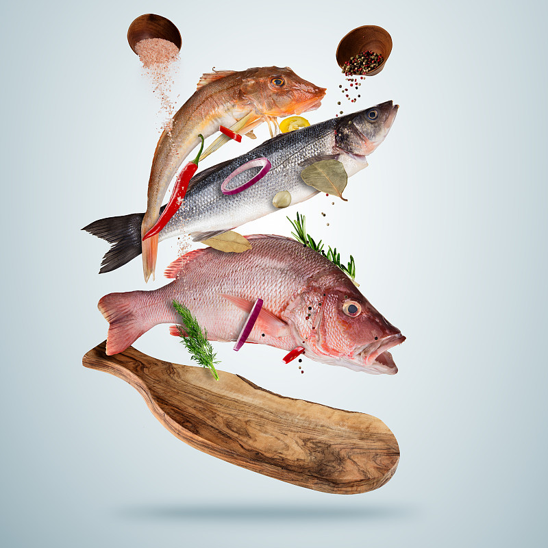 新鲜的海鱼和掉落的香料，飞在木板上