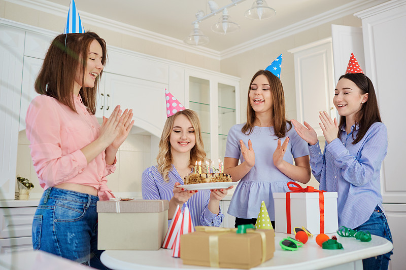 一群女朋友拿着带蜡烛的蛋糕庆祝一只小鸟