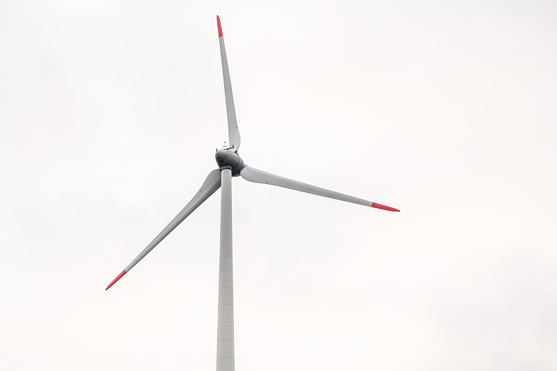 风车螺旋桨映衬着灰色的天空。绿色能源的产生