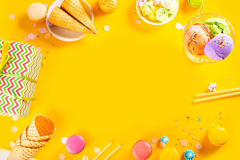 框架的各种彩色冰淇淋勺或球与华夫饼蛋卷在黄色的背景。前视图。副本的空间。