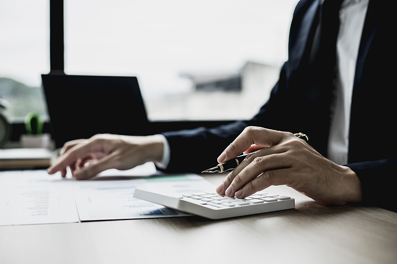 一位商人正在审阅财务文件中的信息，准备将其带到部门和合作伙伴会议上，准备每月的出席信息。财务管理的概念。