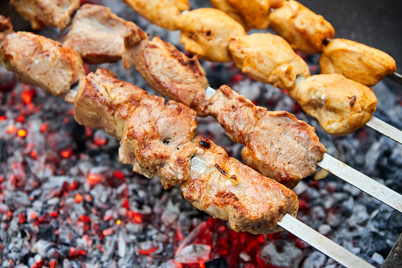 猪肉和鸡肉串在烤架上的烤串上煎
