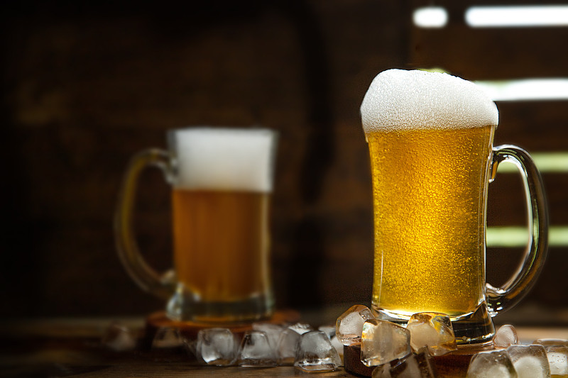 酒吧或酒吧里的新鲜啤酒，用玻璃杯装，背景为深色木质