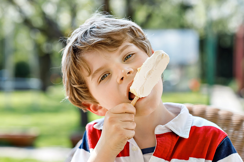 学龄前的小男孩在夏天吃冰淇淋。快乐的孩子和冷甜点。白巧克力冰淇淋。有趣的孩子微笑。