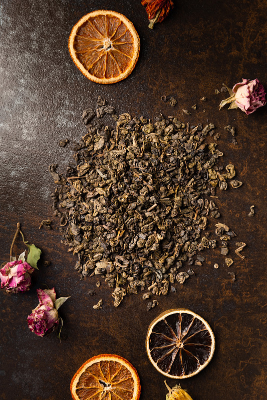 绿茶和干花在棕色背景俯视图。