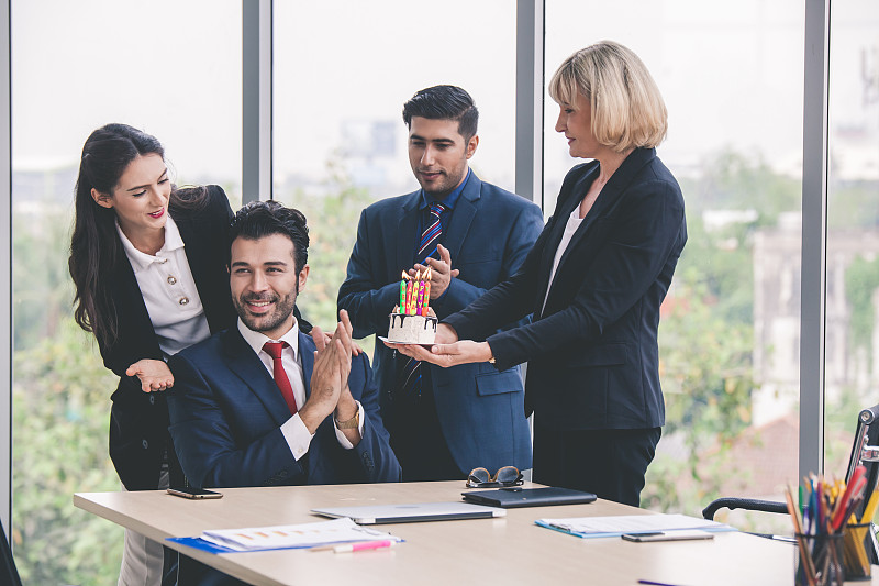 工作团队在办公室用蛋糕庆祝男同事生日。同事们在办公室庆祝生日