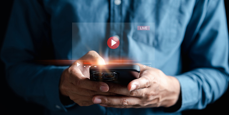 男人触摸智能手机开始直播，在互联网和多媒体上观看屏幕上的视频流，社交技术，社交媒体，技术生活方式。