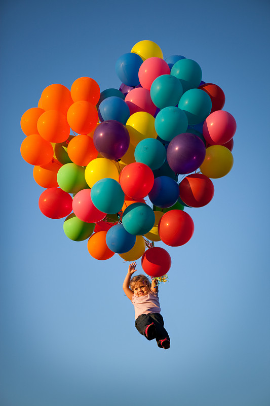 小女孩拿着心形的气球飞走了