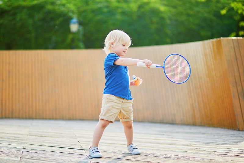 小男孩在操场上打羽毛球