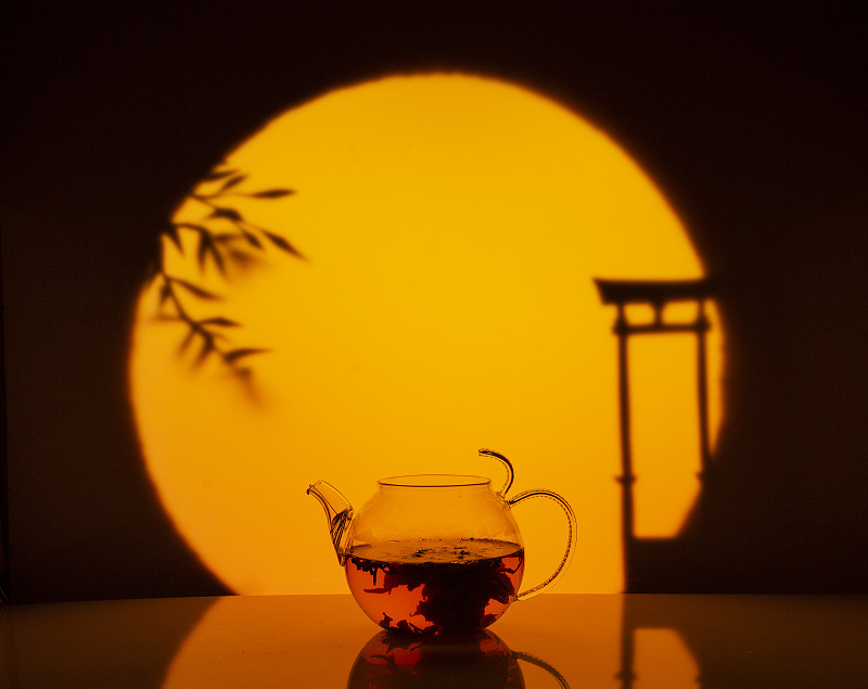 在落日的映衬下，一朵美丽的绿茶花在玻璃茶壶中绽放。