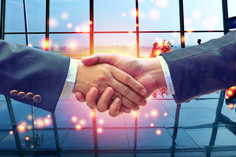 商务人士握手与机场航站楼的抽象背景