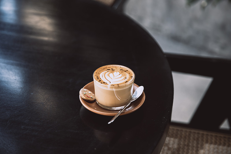 黑色的桌子上放着一杯放着拉花的卡布奇诺