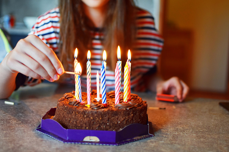 女孩用手在蛋糕上点上条纹生日蜡烛
